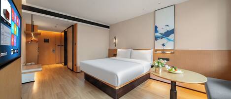 A hotel room with a bed, a desk, a chair, a TV, and a painting on the wall.