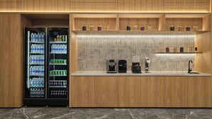 Una cocina moderna con armarios de madera, encimera de mármol, máquina de café y dispensador de agua.
