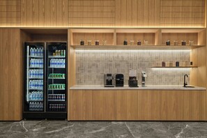 Una cocina moderna con armarios de madera, encimera de mármol, máquina de café y dispensador de agua.