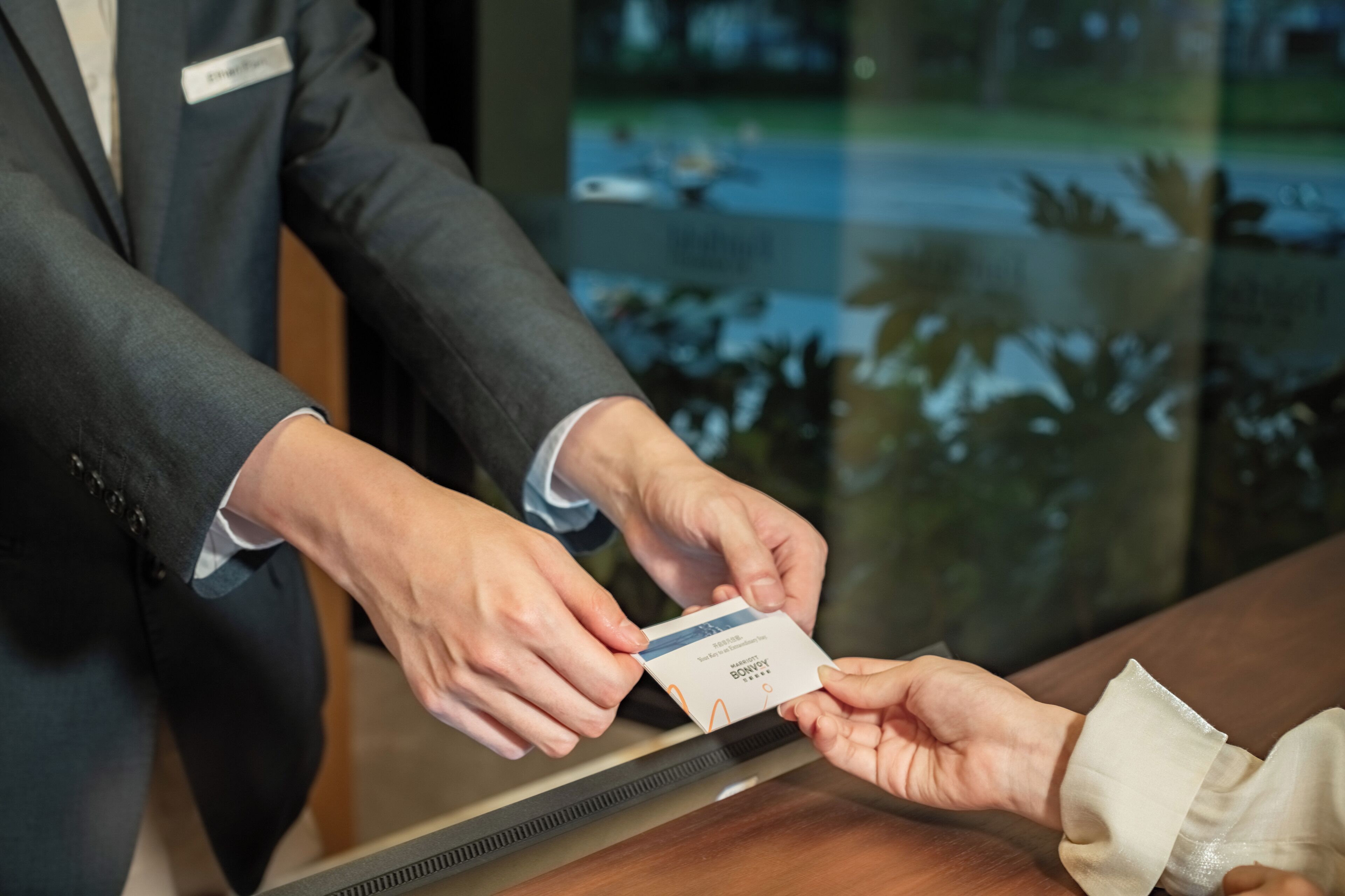 A person handing over a card to another individual at a reception desk.