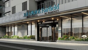 Fachada moderna de un hotel con un cartel llamativo que dice "Fairfield by Marriott" y una entrada de vidrio.