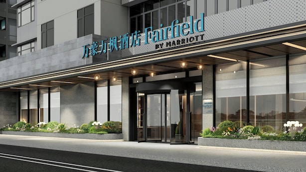 Fachada moderna de un hotel con un cartel llamativo que dice "Fairfield by Marriott" y una entrada de vidrio.