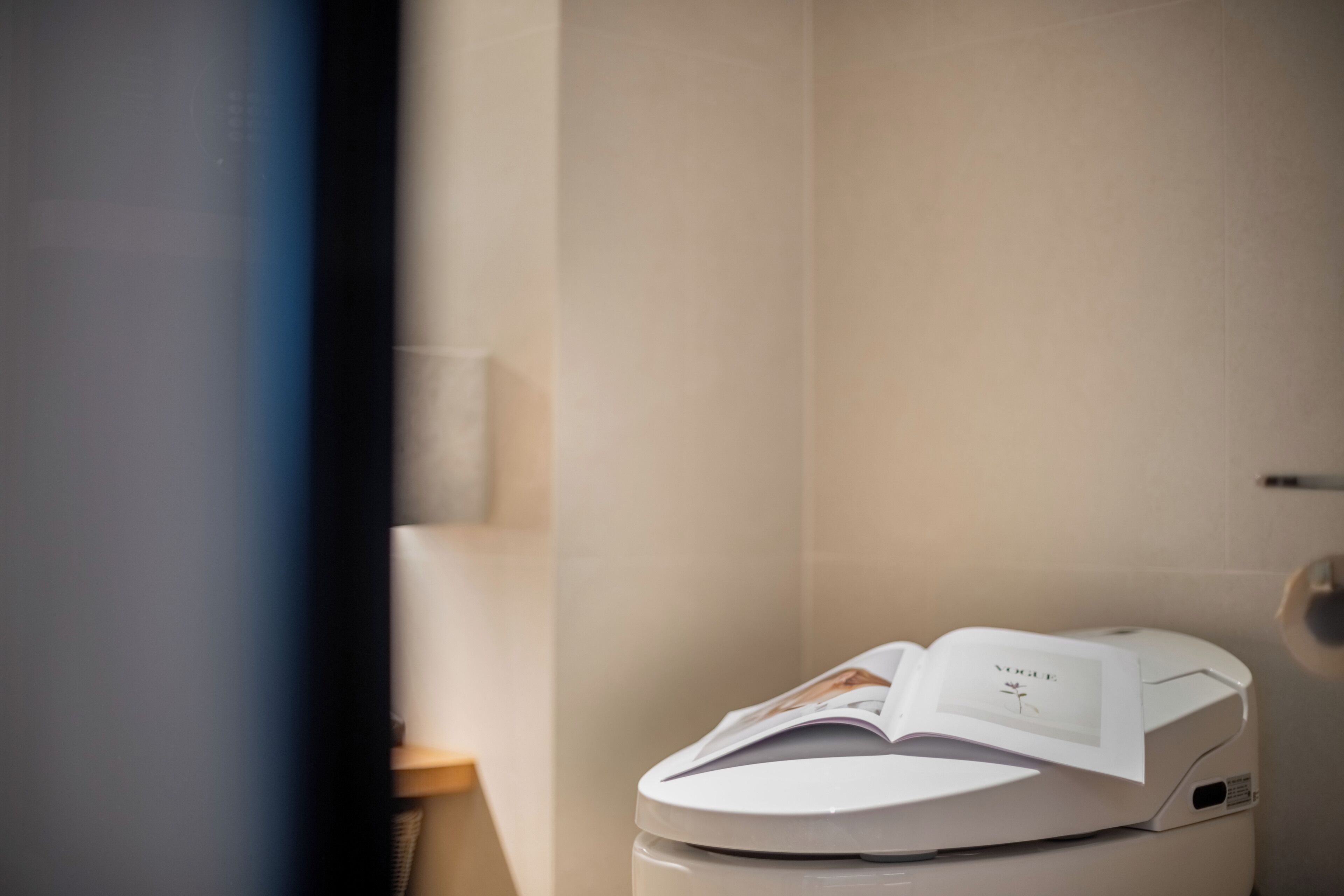 A modern toilet with a magazine on top.
