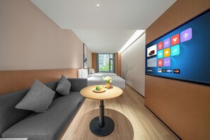 Ein modernes Wohnzimmer mit einer Couch, einem runden Tisch mit Blumenvase und einem großen, an der Wand befestigten Fernseher, der verschiedene Apps anzeigt.