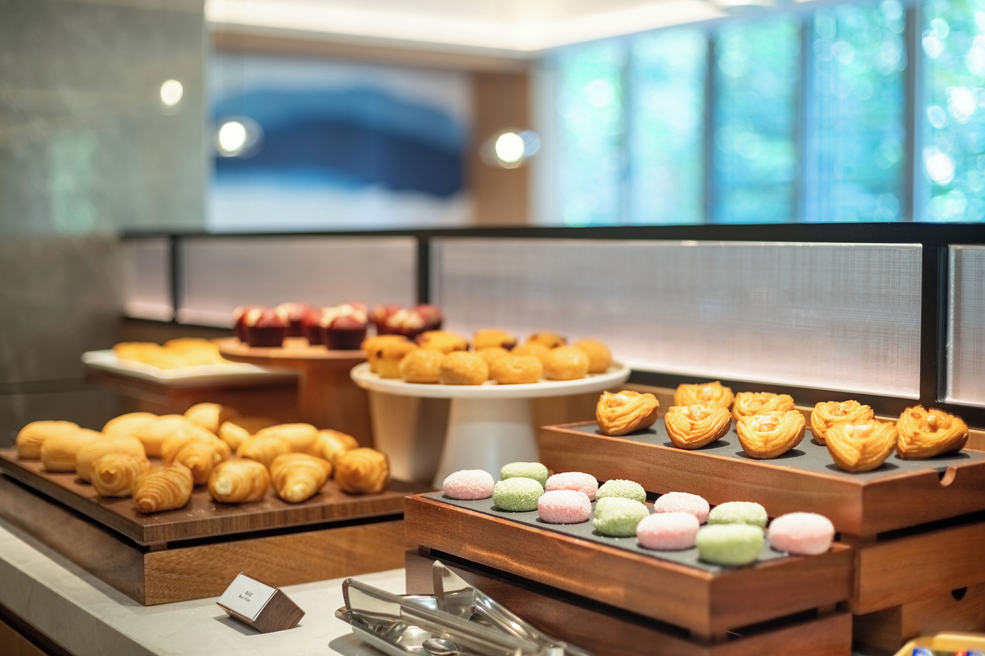 A variety of pastries and desserts displayed in a bakery section with a modern interior design.
