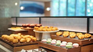 A variety of pastries and desserts displayed in a bakery section with a modern interior design.