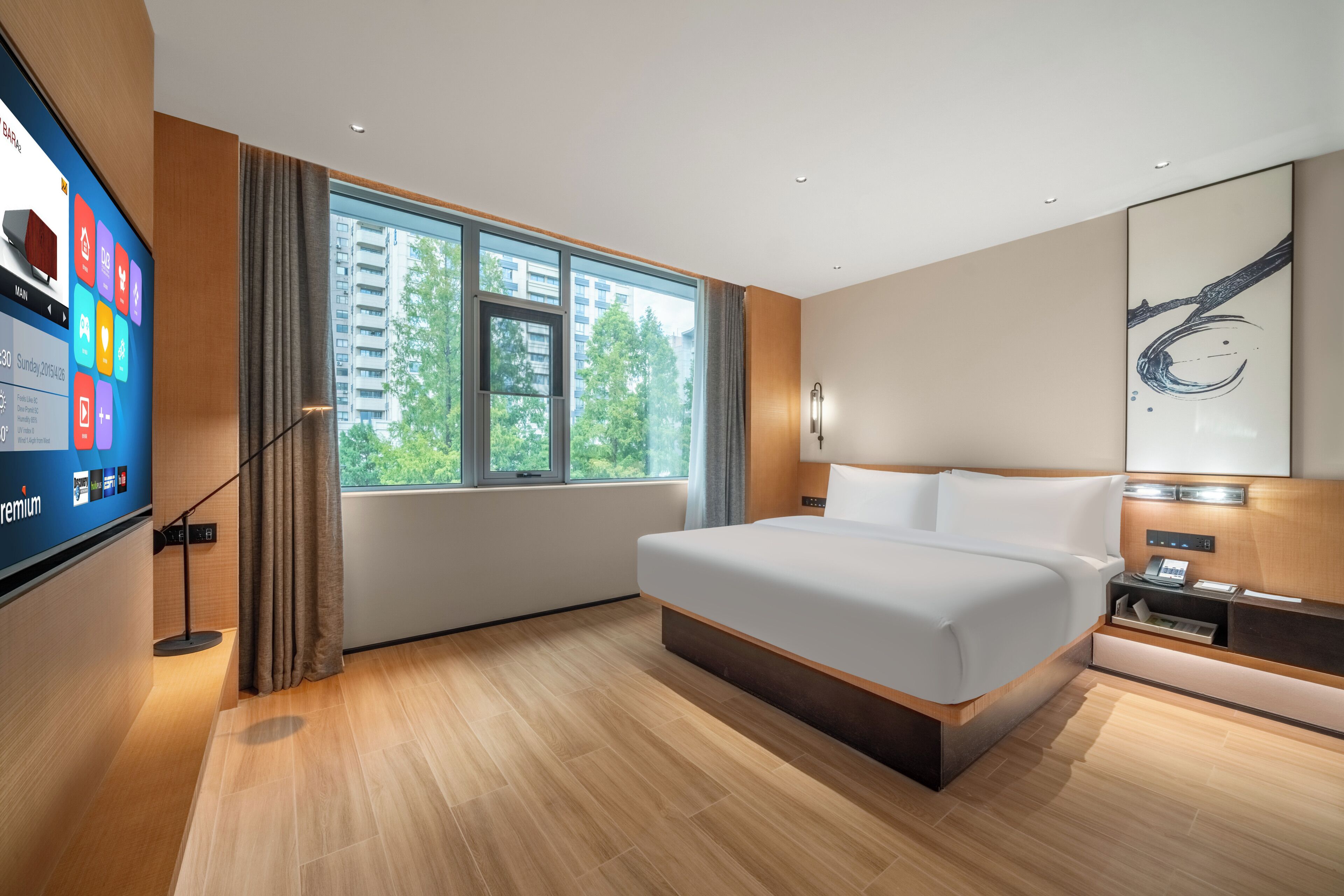 Una habitación de hotel moderna con una cama grande, un televisor en la pared y vistas a la ciudad.