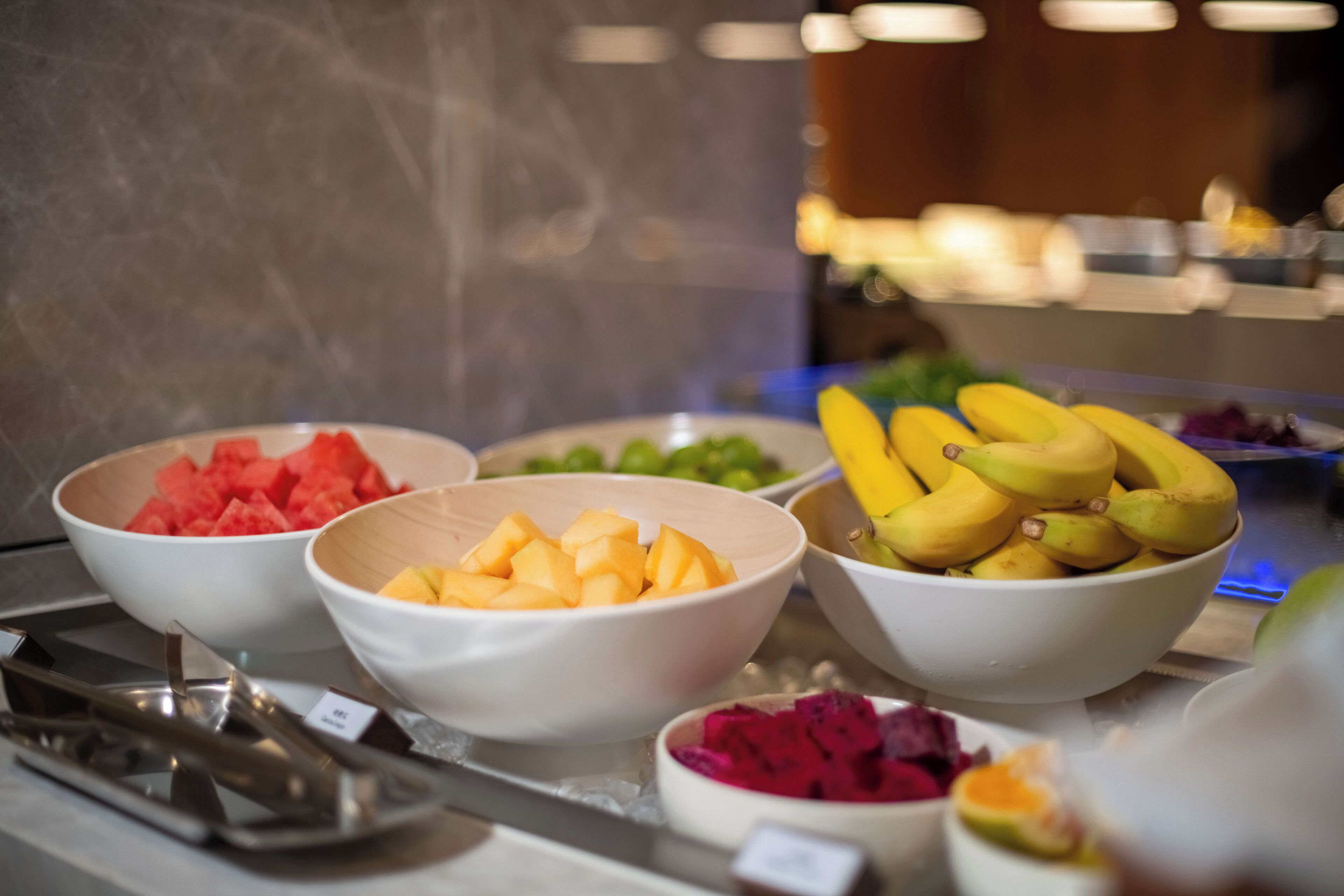 A buffet with various fruits including watermelon, mango, bananas, and dragon fruit.