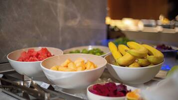 A buffet with various fruits including watermelon, mango, bananas, and dragon fruit.