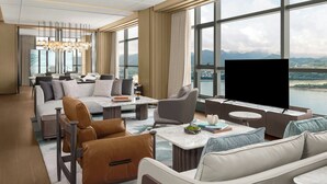 Une chambre d’hôtel moderne dotée d’une grande fenêtre donnant sur la ville, d’un téléviseur à écran plat et d’un coin salon confortable avec un canapé et des fauteuils.