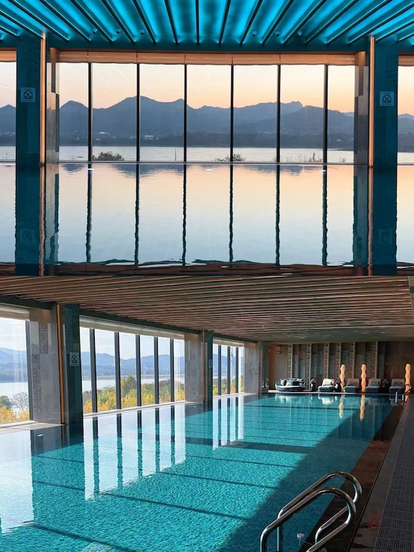 En stor inomhuspool med utsikt över berg och en sjö eller annat vattendrag.
