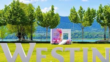 Une grande enseigne extérieure avec le mot « WESTIN » en lettres majuscules, entourée d’un élément décoratif aquatique et d’arbres.