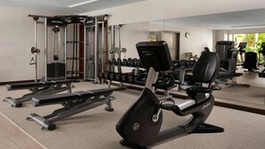 Une salle de sport équipée de machines de cardio, de machines de musculation et de poids libres.