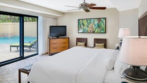 Ein Hotelzimmer mit einem großen Bett, einem Fernseher, einem Deckenventilator, einem Gemälde und Blick auf einen Swimmingpool.
