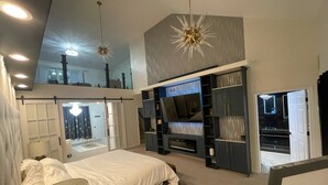 A bedroom with a bed, a TV, and built-in shelving. - Beach Park Estate: Chef's Kitchen, Nature, Fitness Room, Naval Base, Beach, Lake (Beach Park)