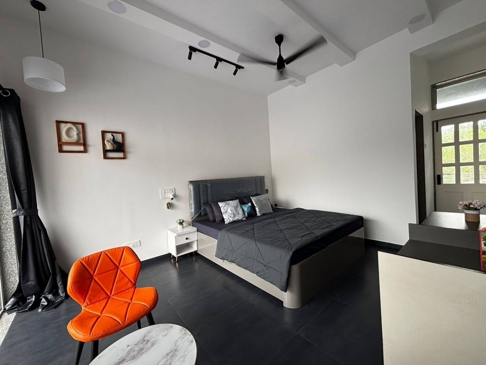 Une chambre moderne avec un lit, une chaise, une table et un ventilateur de plafond.
