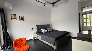 Une chambre moderne avec un lit, une chaise, une table et un ventilateur de plafond.