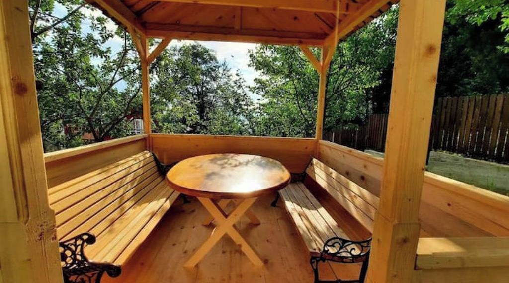 A wooden gazebo with a round table and benches.