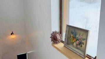 Un coin de pièce avec une fenêtre, un cadre photo et une petite étagère.