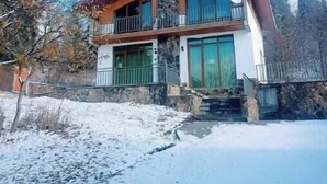 Un immeuble de deux étages avec une façade en pierre, de grandes fenêtres et un balcon.