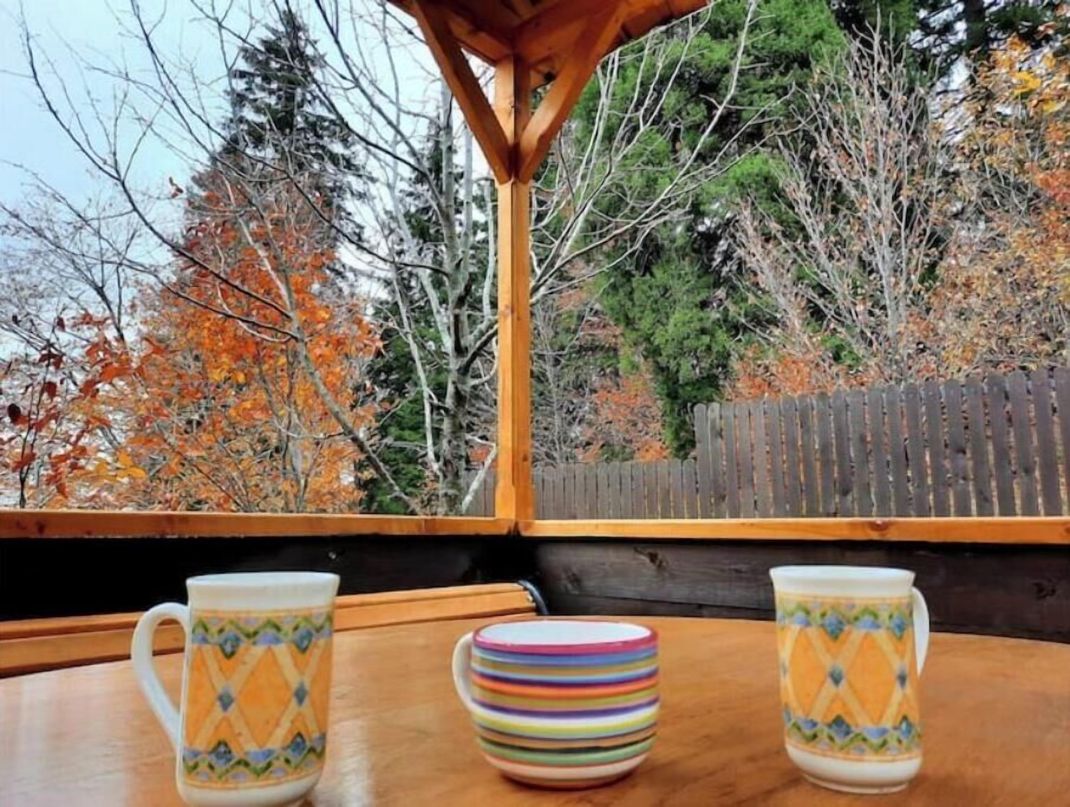 Un tavolo di legno con due tazze decorate e una pila di piatti colorati.