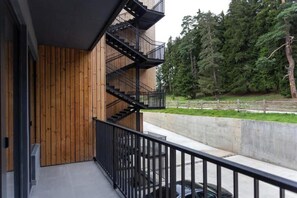 A modern building with a wooden facade and a black metal staircase leading to a balcony. - Charming 1BR Apartment (Georgia  Bakuriani)