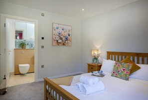 Ein Schlafzimmer mit einem hölzernen Bett, weißer Bettwäsche, einem Nachttisch mit Lampe und einem Bild an der Wand.