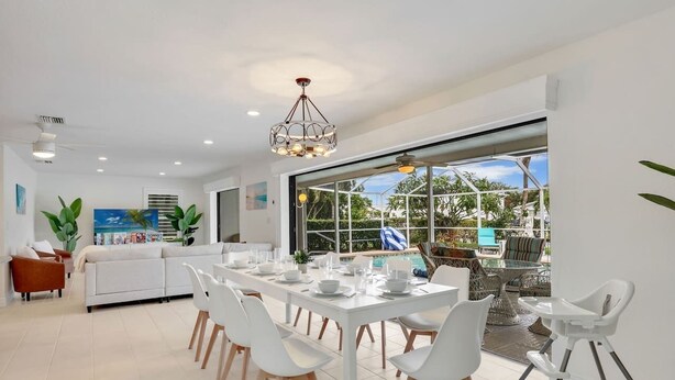 A modern kitchen with a dining area, large windows, and a view of the outdoors. - Waterfront Home with Heated Pool, Air Hockey, Beach Gear & MORE! (Cape Coral)
