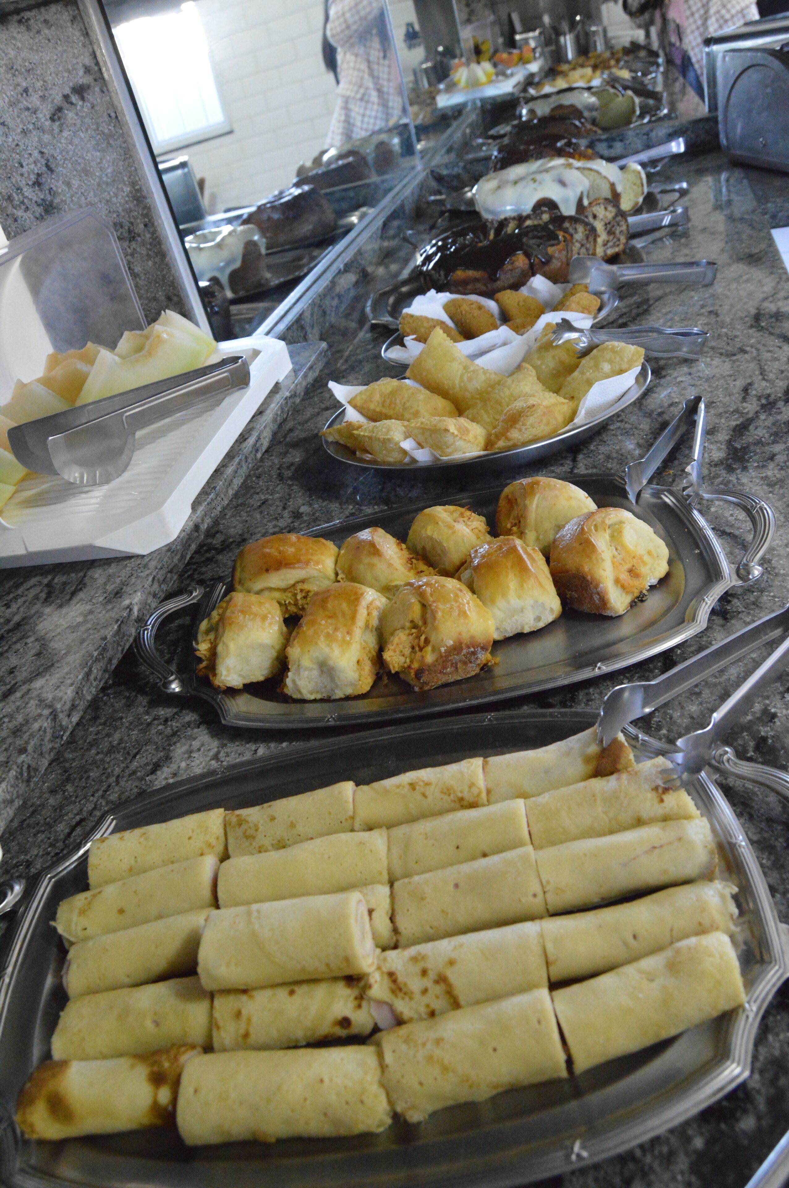 A buffet with various food items including pastries and rolls.