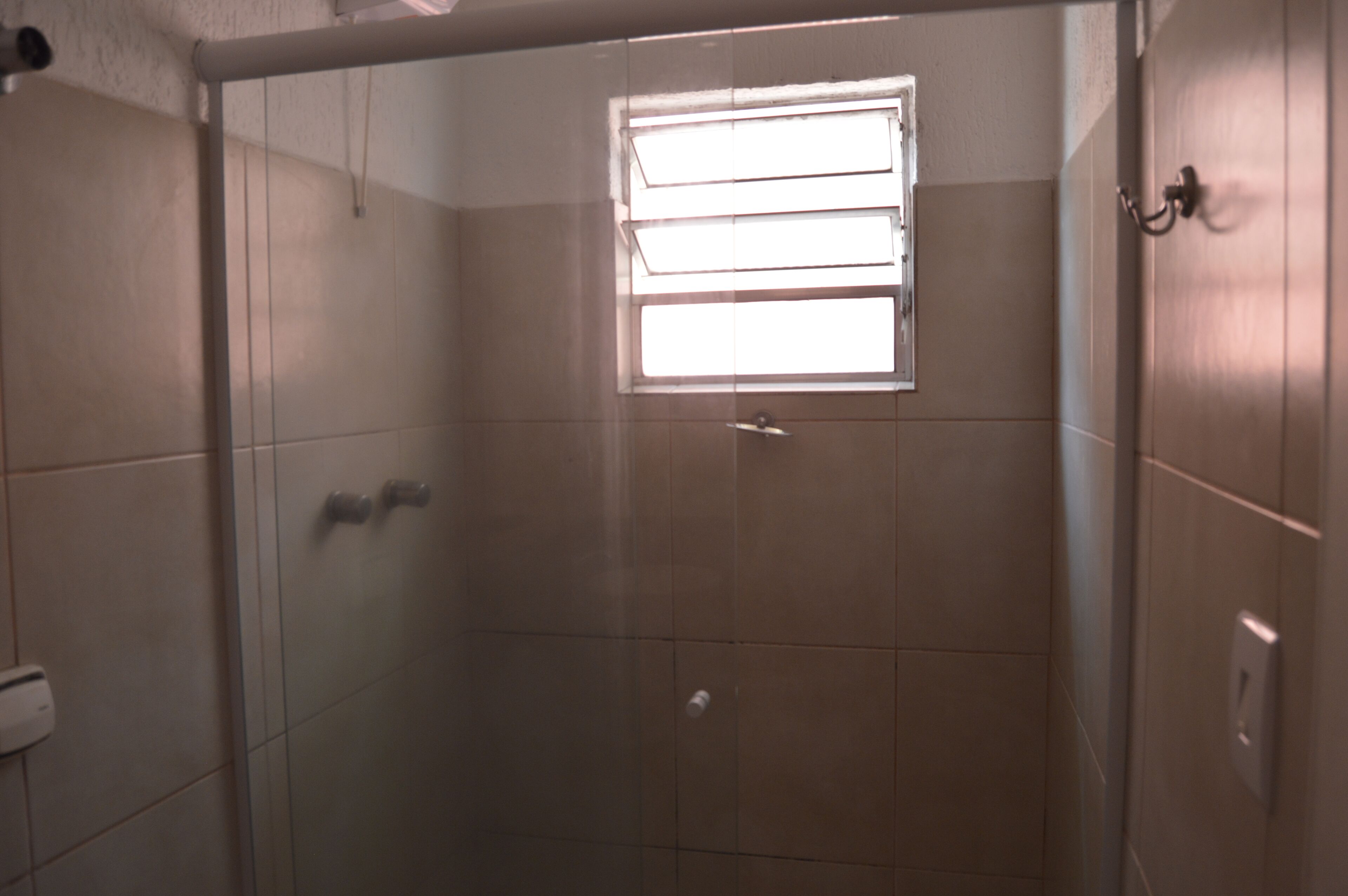 A shower area with a window, tiled walls, and a door.