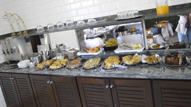 A buffet counter with various food items and utensils. - Hotel Cuca Fresca (Cotia)