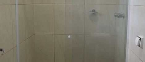 A bathroom with a glass-enclosed shower, a toilet, and a sink with a black countertop.