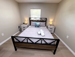 Ein Schlafzimmer mit einem Bett, Nachttischen, einem Fenster und einer Steckdose.