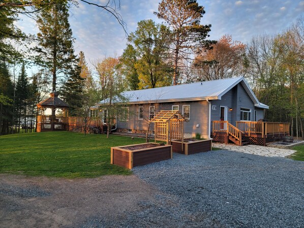 A cabin with a deck, a covered porch, and a garden area.