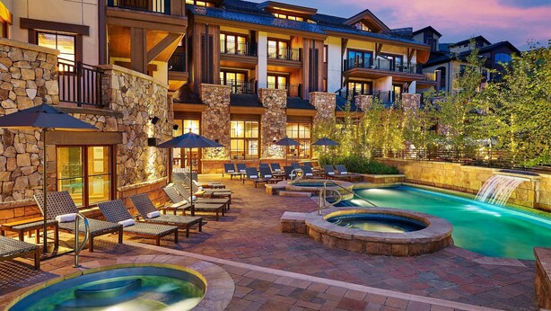 Un resort con zona de piscina, sillones de descanso y una cascada.