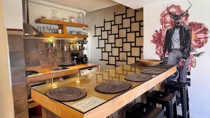 A modern kitchen with a wooden countertop, a built-in stove, and a decorative wall with a geometric pattern.