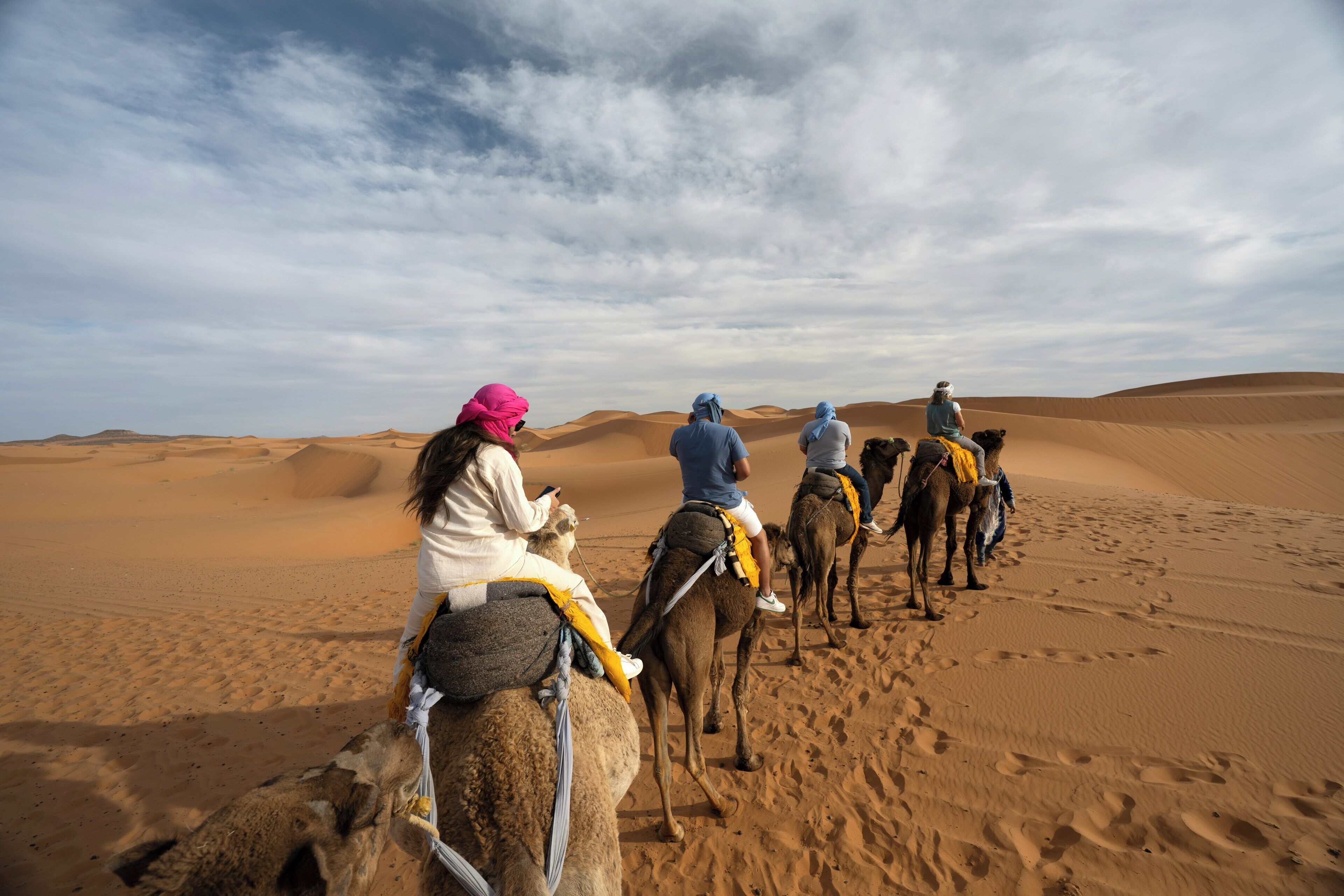 A group of people riding camels across a desert landscape.