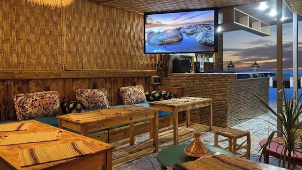 Une pièce confortable, dotée de meubles en bois, d’une télévision et offrant une vue sur la mer.