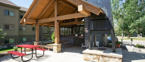 An outdoor patio with picnic tables and a grill area.