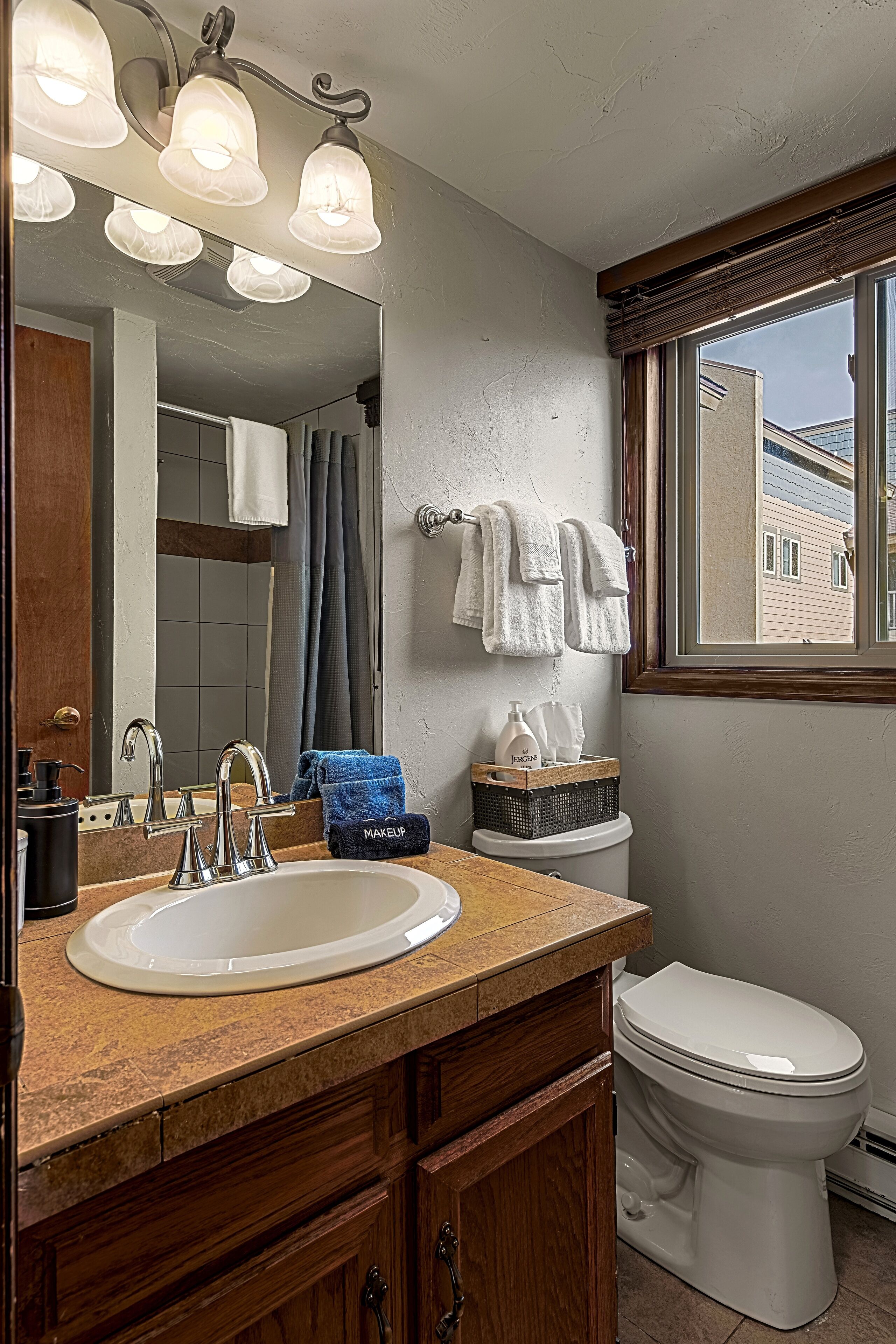 Ein Badezimmer mit Waschbecken, Spiegel, Handtuchhalter und Toilette.