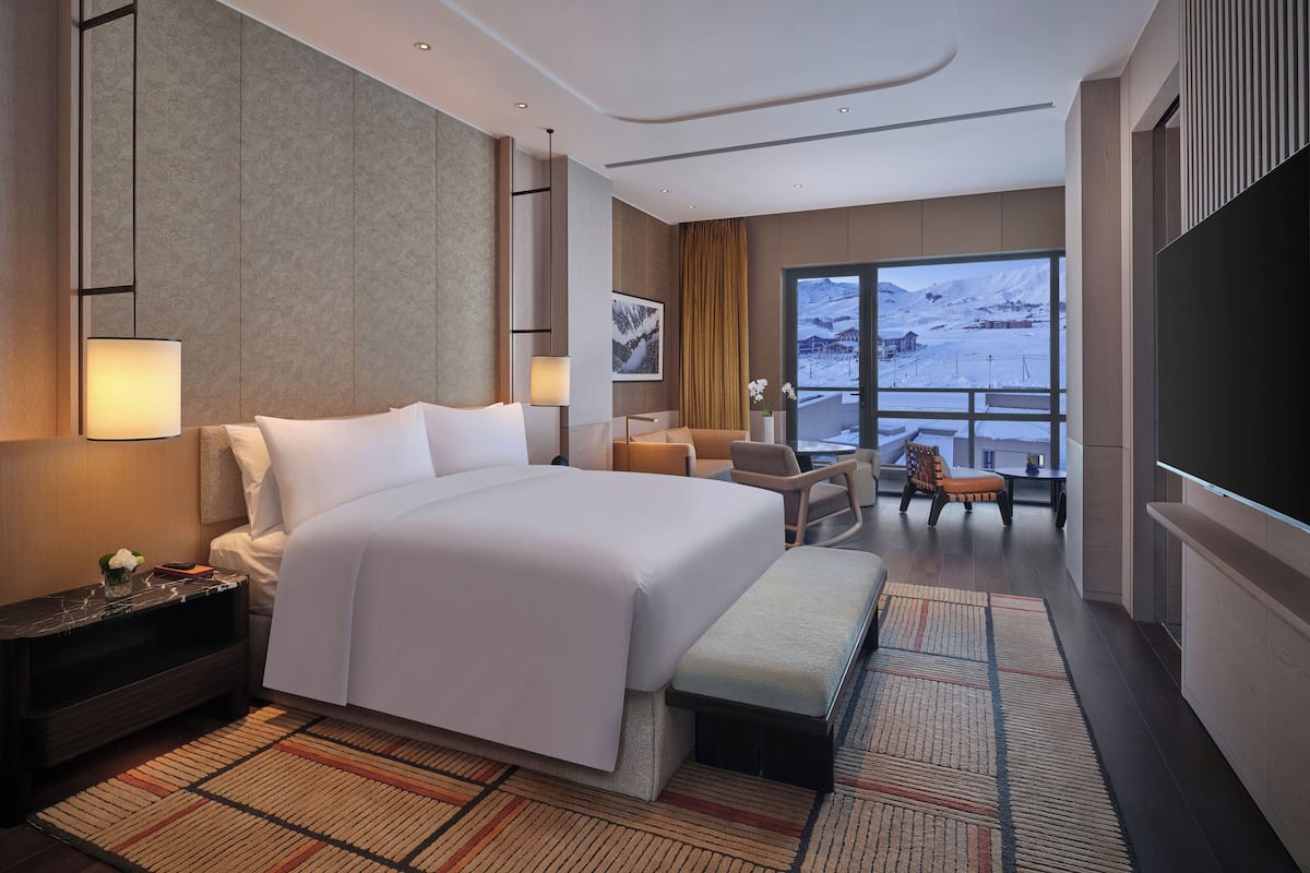 Una habitación de hotel moderna con una cama grande, un escritorio, una silla y un televisor.