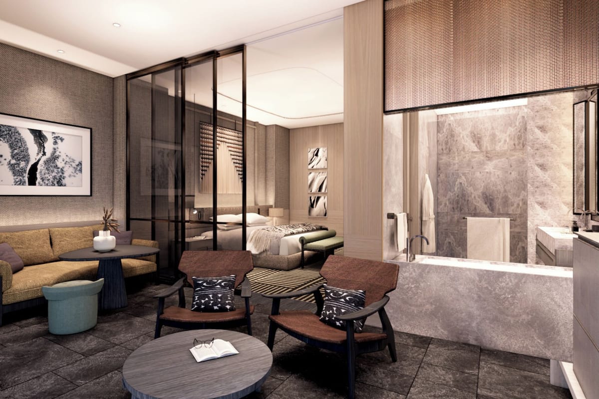 Una habitación de hotel moderna con sofá, sillones, una mesa de centro, cama y baño con bañera, además de un ventanal grande.