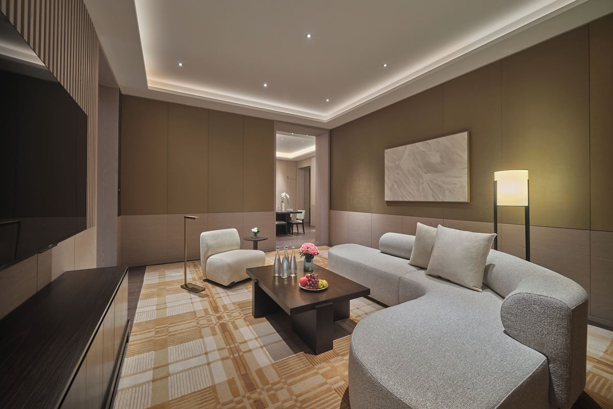 Una sala de estar moderna con un sofá, sillones, una mesa de centro y un televisor.