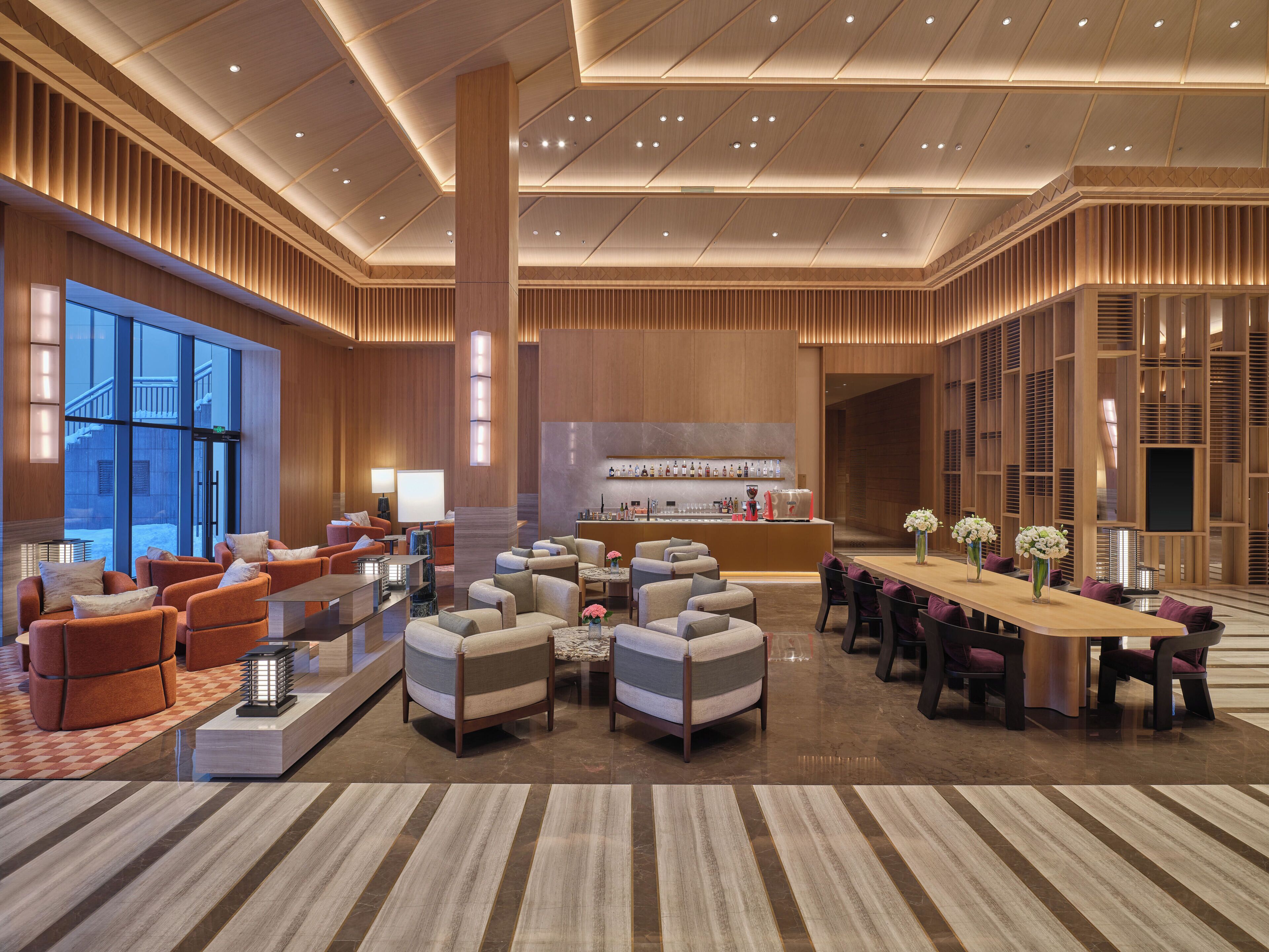A spacious lobby with a reception desk, seating area, and large windows.