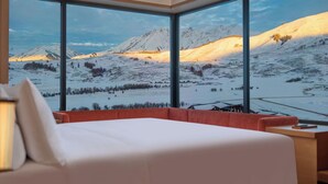 A bedroom with a large window offering a view of snow-covered mountains. - Hilton Altay Hemu (Burqin)