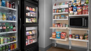 Een ruimte voor zelfbediening met drankkoelingen, snacks en een magnetron.