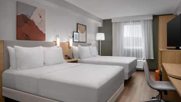 Habitación de hotel con dos camas, un escritorio, una silla, un televisor y una ventana con cortinas.