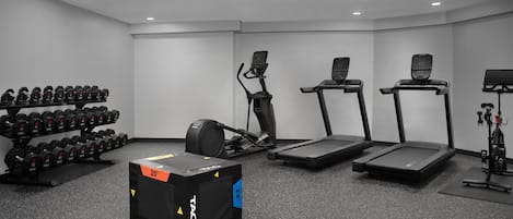 Een fitnessruimte met loopbanden, elliptische trainers en een dumbbellsrek.