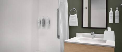 A modern bathroom with a bathtub, a sink with a mirror, and toiletries on the wall.