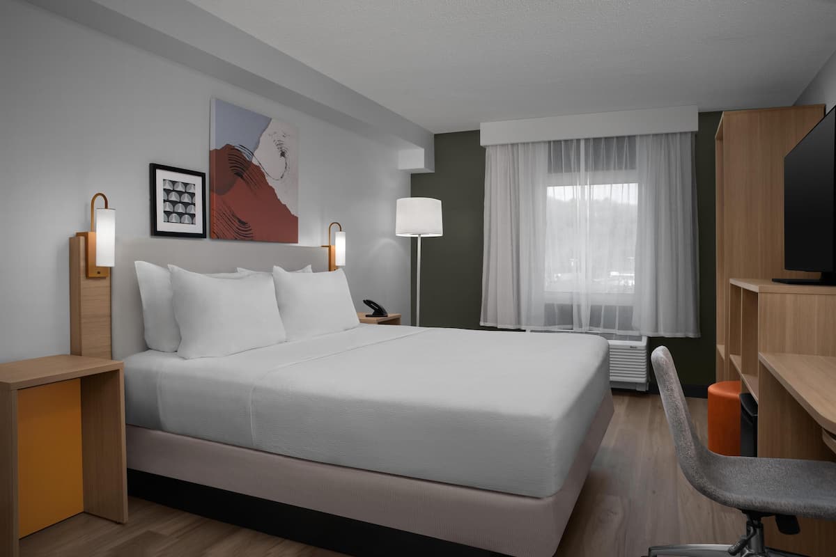Een moderne hotelkamer met een groot bed, bedlampen, een bureau en een televisie.